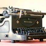 Collezione di vecchie macchine da scrivere vintage esposte su un tavolo di legno.